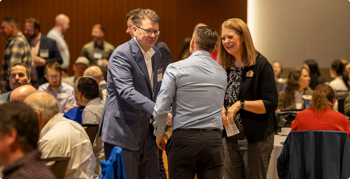 Three people meeting at a packed event.