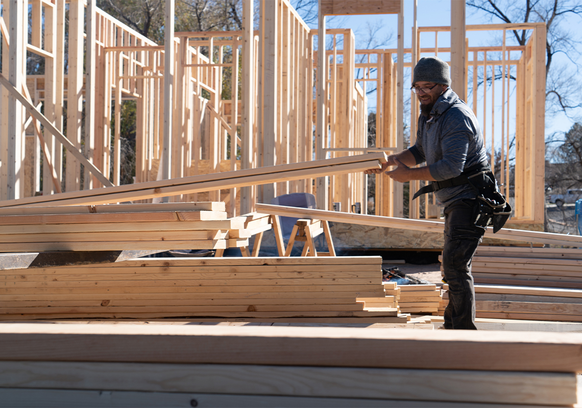 Construction worker moving lumber